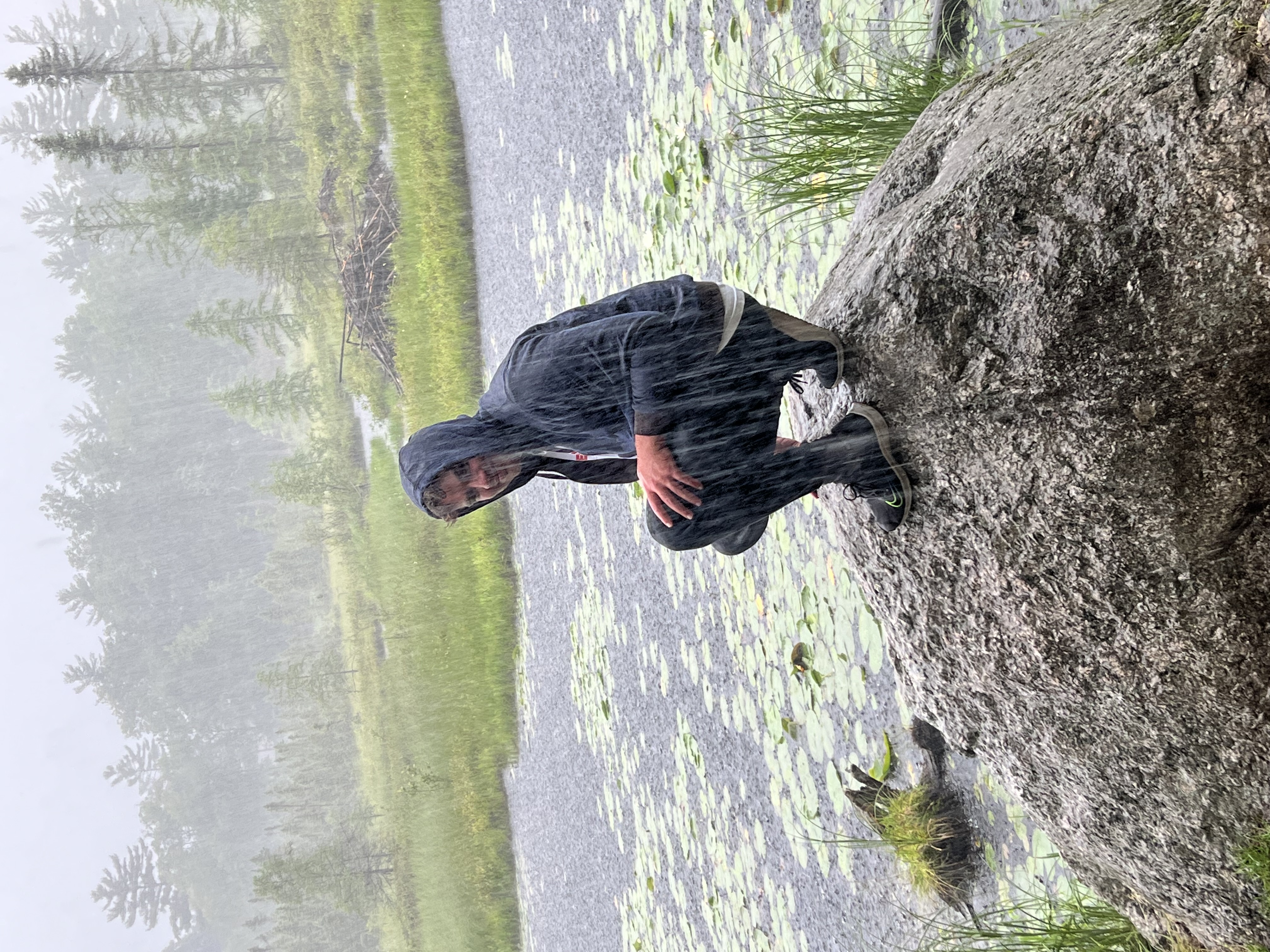 Ryan sitting on rock while in the rain